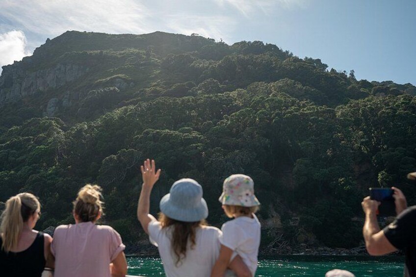 A group of people on a boat, facing a mountainous landscape. 2