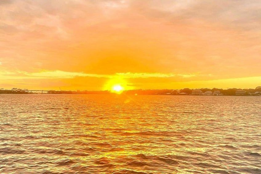 Un atardecer sobre un cuerpo de agua con un puente a lo lejos. 2