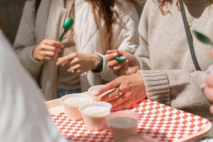 Persone che tengono cucchiai verdi, una tovaglia a quadri e bicchieri di plastica con bevande. 3