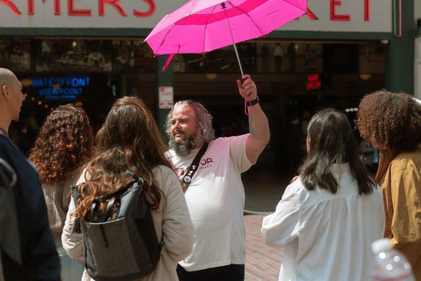 En grupp människor som går på en trottoar med en butiksfasad i bakgrunden. 5