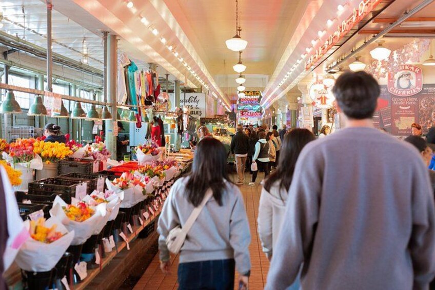 Un mercado cubierto donde la gente observa puestos que venden flores y mariscos. 1