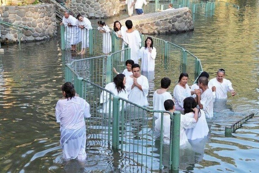 Des personnes vêtues de longues robes blanches se tiennent sur un pont qui enjambe une étendue d’eau. 1