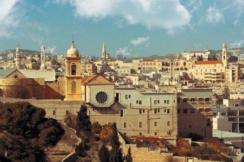 Un paysage urbain avec des bâtiments historiques, dont une église dotée d’un clocher et d’un dôme, le tout entouré de constructions modernes. 2