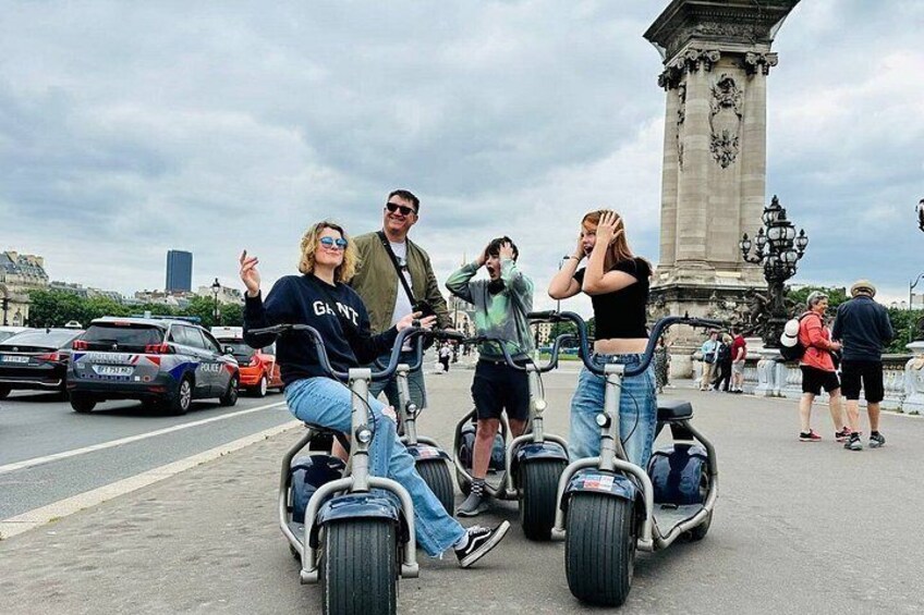 Personas montando segways por una calle de la ciudad, con un monumento al fondo. 1