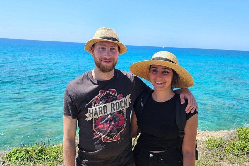 Two people standing by a turquoise sea with a clear sky. 3