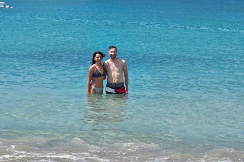 Two people standing in shallow water at a beach with clear blue water. 5