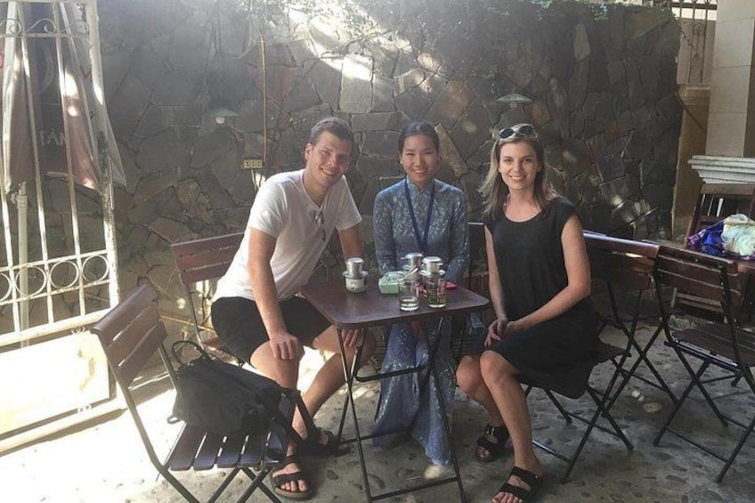 Three people sitting at an outdoor table with a stone wall in the background. 3