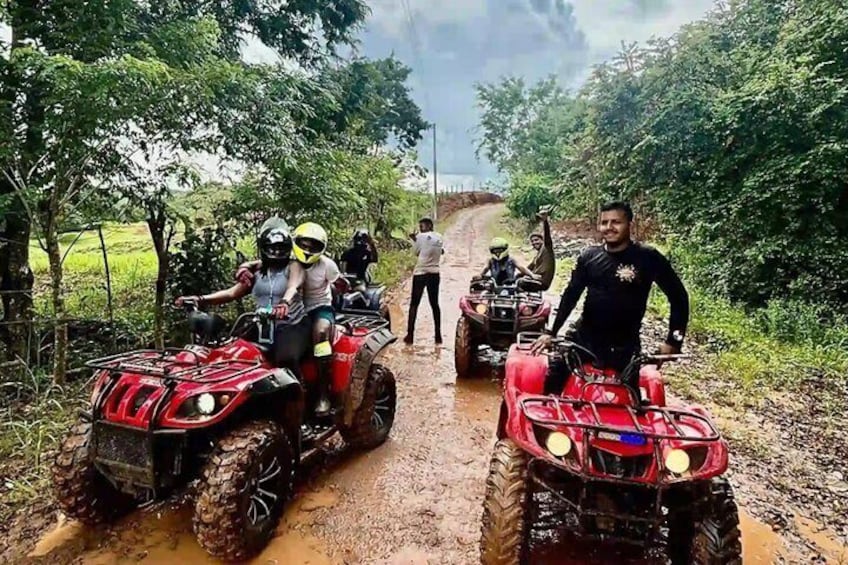 Persone che guidano quad attraverso un sentiero fangoso, circondati da vegetazione. 3
