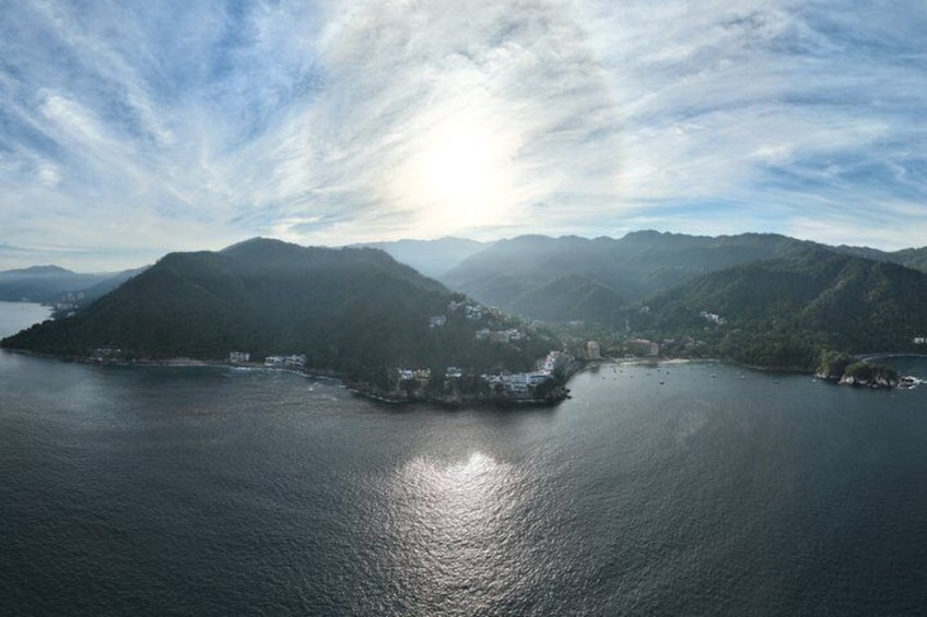 A coastal landscape with a large body of water, a small island with buildings, and a mountainous backdrop. 2