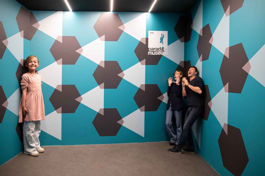 A child and two adults in a room with geometric patterns and a 'paradise museum' sign. 5