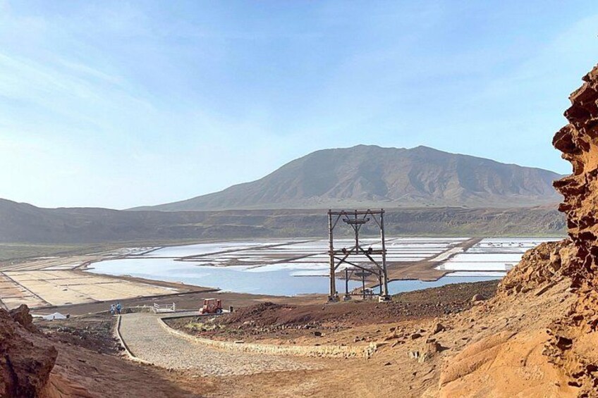 A dry riverbed with a power line structure, a distant mountain, and a rocky terrain. 3