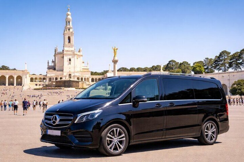 Una furgoneta negra Mercedes-Benz Sprinter estacionada frente a un edificio histórico con una alta torre de campanas. 5