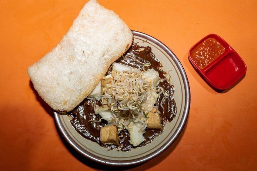 En skål med mad, et stykke brød og en beholder med rød sauce. 5