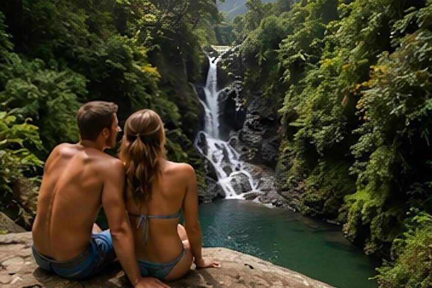 A couple sitting by a waterfall in a lush green forest. 5