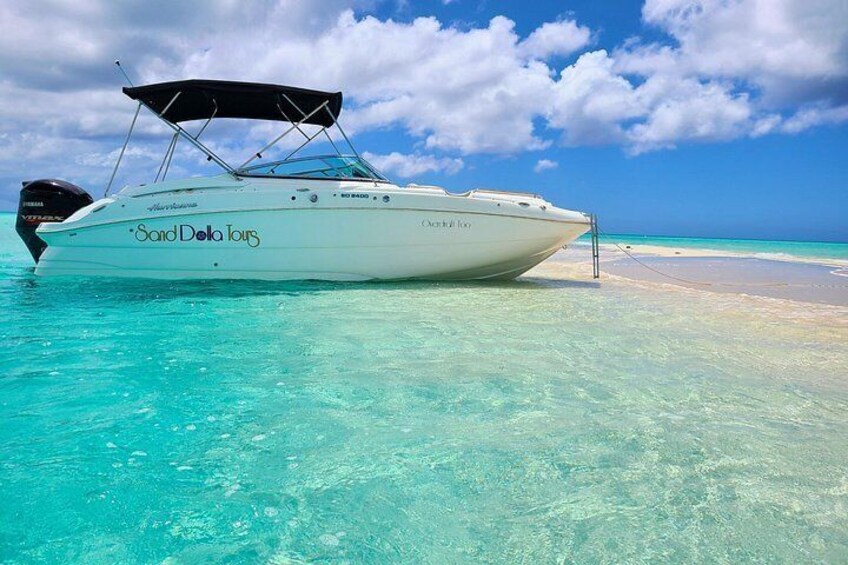 A boat named 'Sand Dole Tours' anchored near a beach with clear turquoise water. 1