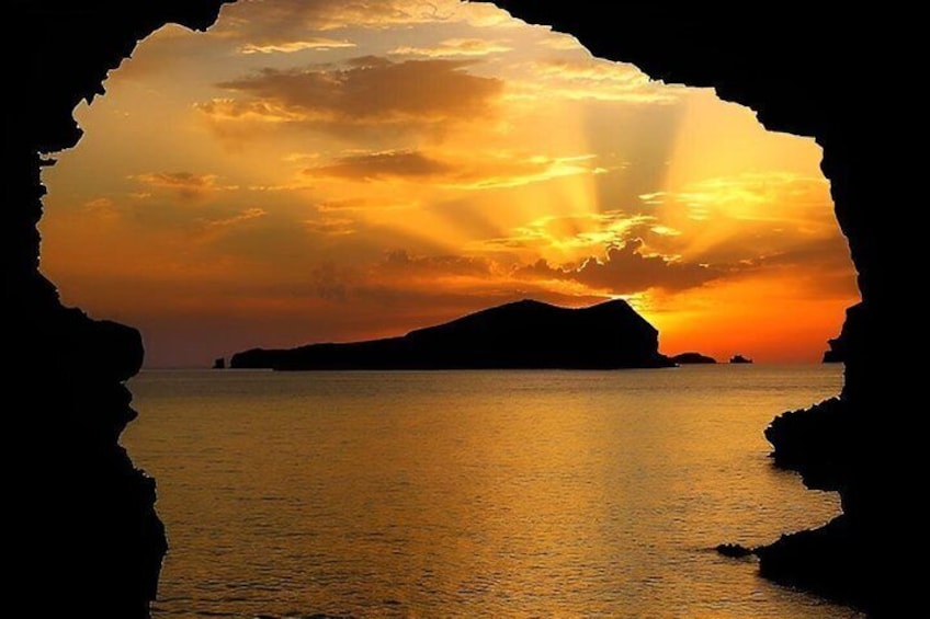 Un coucher de soleil sur une mer calme, avec la silhouette d’une montagne et d’une île lointaine. 5