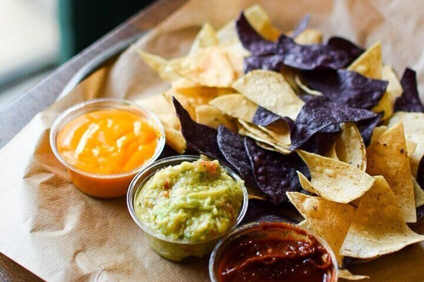 Tortilla chips, guacamole, and salsa on a wooden tray. 2