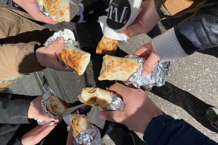 People holding food items wrapped in foil. 1