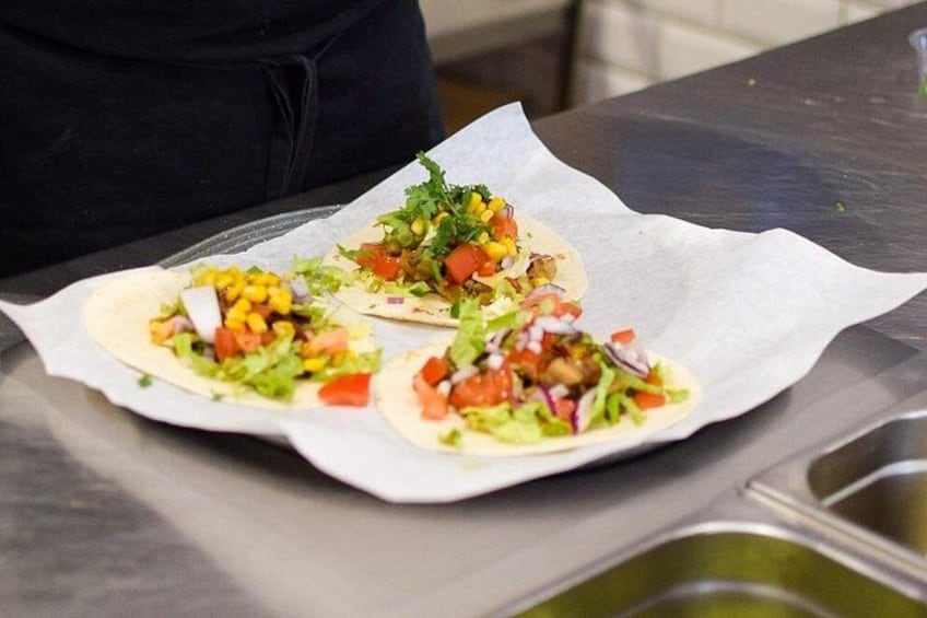 Two tacos on a metal surface with a paper liner. 3