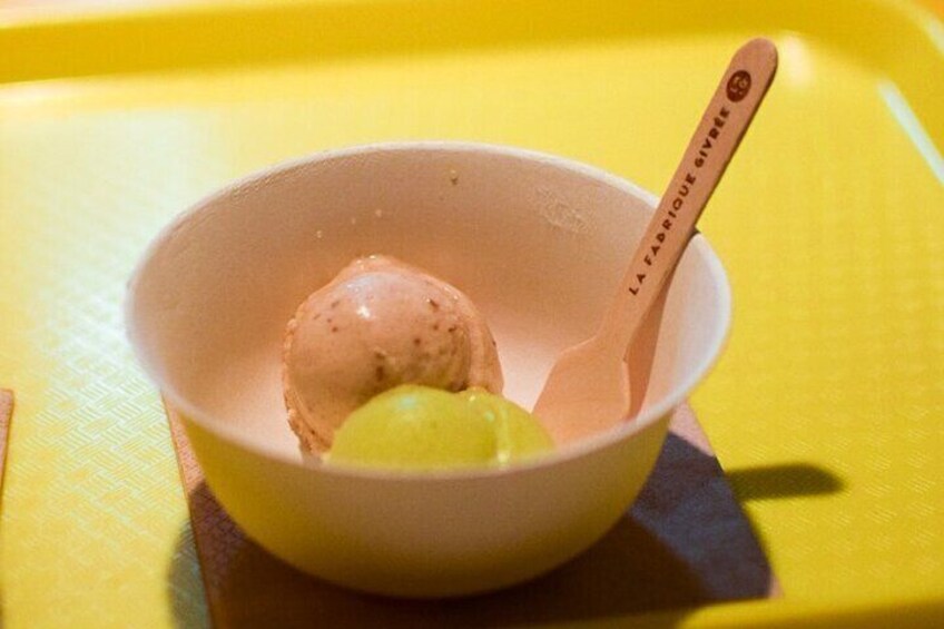 A bowl of ice cream with a wooden spoon on a yellow surface. 3