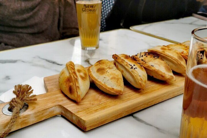 A wooden board with pastries and a glass of beer on a table. 4