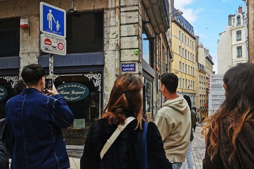 A street scene with pedestrians, a sign indicating a pedestrian crossing, and a cafe sign. 2