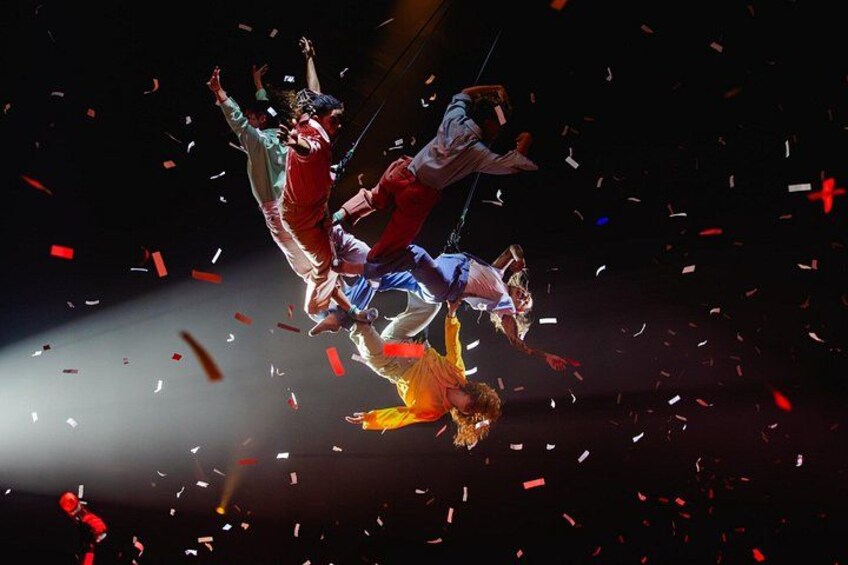 Acrobats performing synchronized aerial maneuvers with confetti falling around them. 3