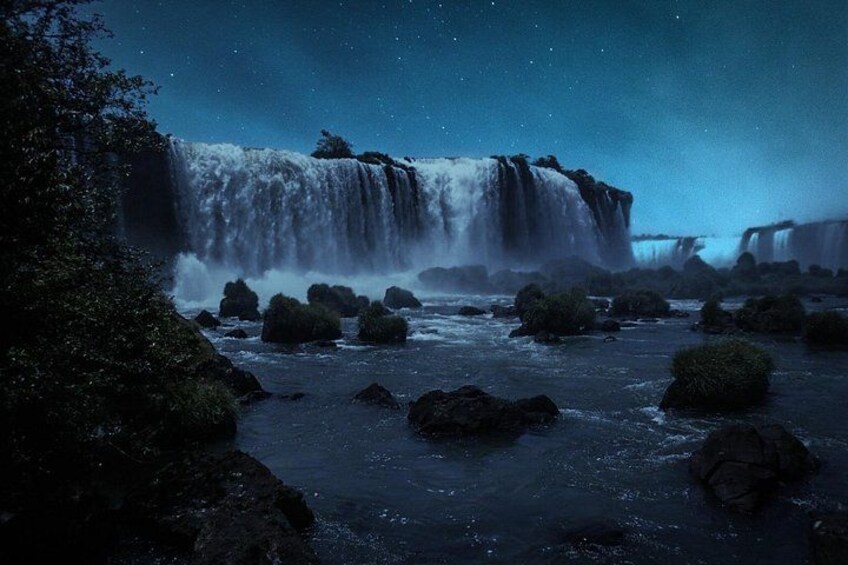 A waterfall at night with rocks in the foreground. 4