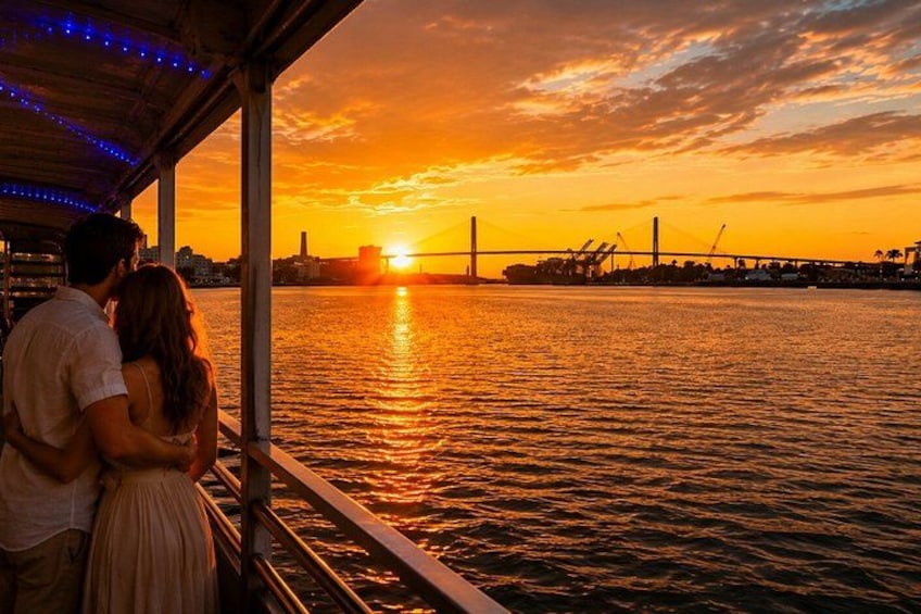Un atardecer sobre una masa de agua con un puente al fondo. 1