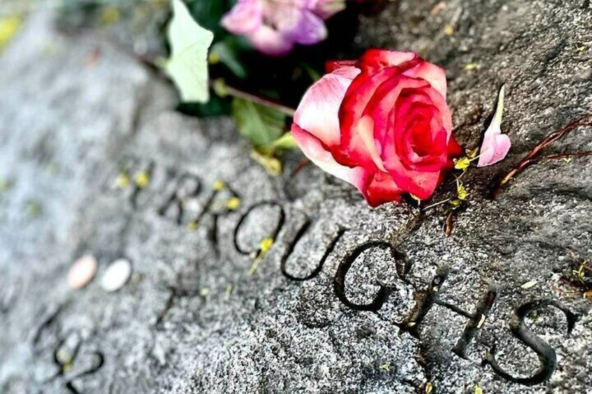 A red rose on a gravestone with the name "THROUGH" partially visible. 1