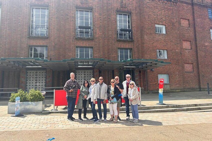 A group of people standing in front of a brick building with a covered entrance. 4
