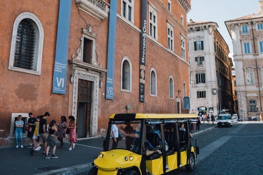 A yellow taxi, tourists, and historic buildings. 1