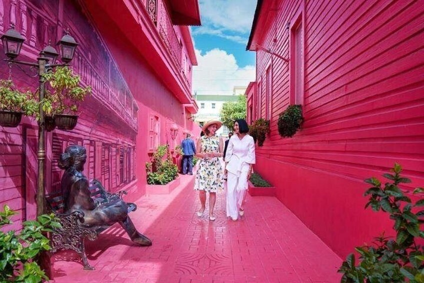 A red building with a statue of a woman and a street lamp. 2