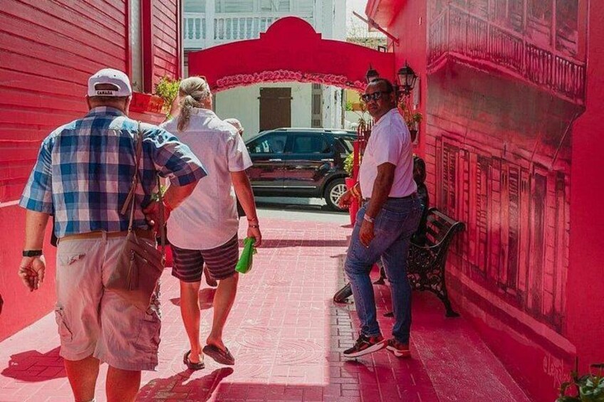 A red building with a white door, a person walking with a green bottle, and another person standing by a bench. 5