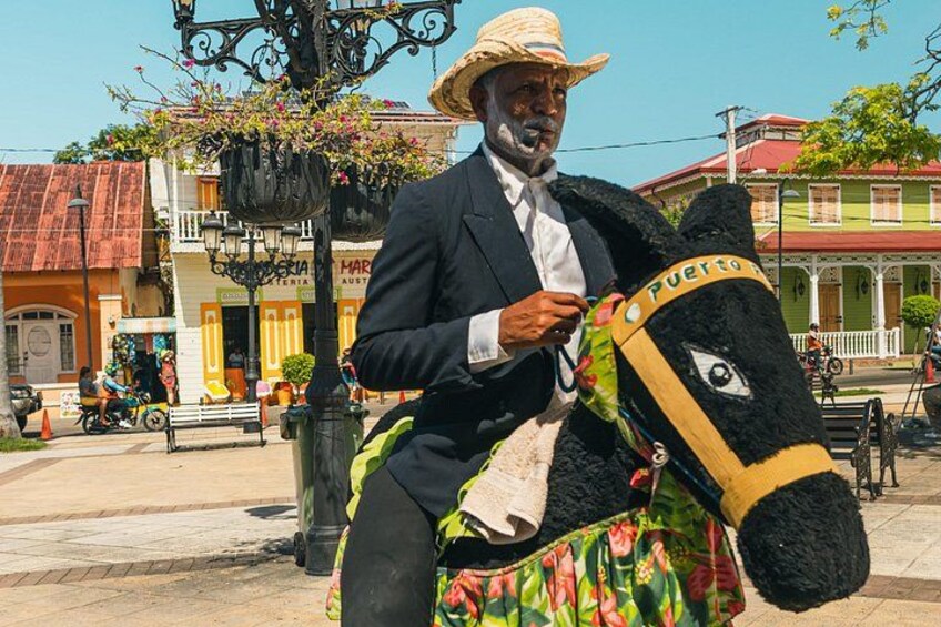 A man in a suit and hat riding a donkey with a Puerto Rico sign. 4
