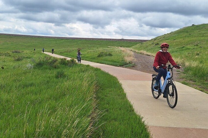 Un ciclista en un camino pavimentado a través de un campo cubierto de hierba. 3