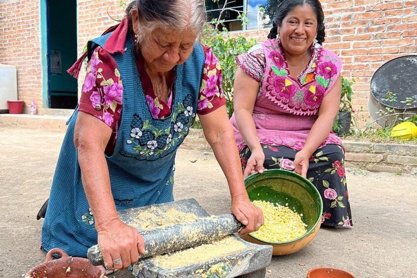 Two women grinding corn with a stone mill. 1