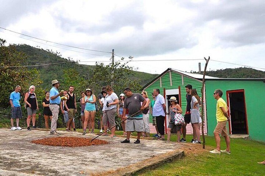 A group of people gathered around a green building with a red door, standing on a concrete platform. 4