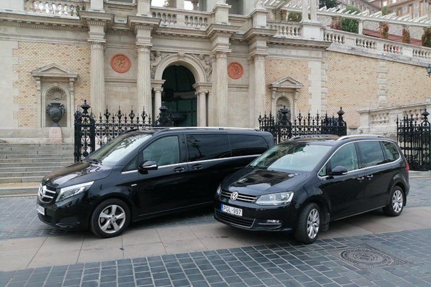 Zwei schwarze Autos sind vor einem historischen Gebäude mit aufwendiger Architektur geparkt. 2