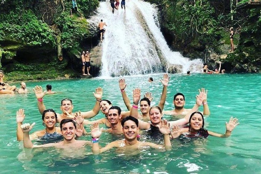 A group of people in a natural pool with a waterfall in the background. 2
