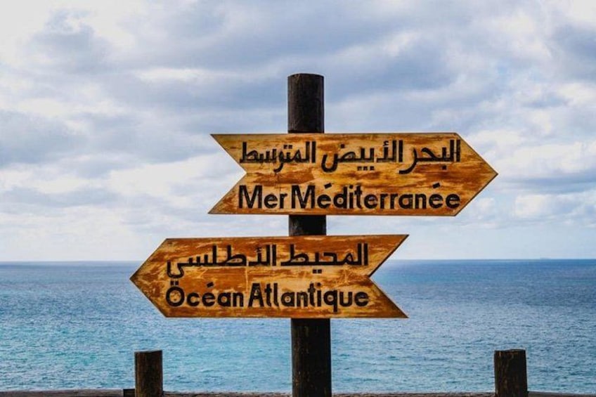 A wooden signpost with arrows pointing to the Mediterranean Sea and the Atlantic Ocean. 1
