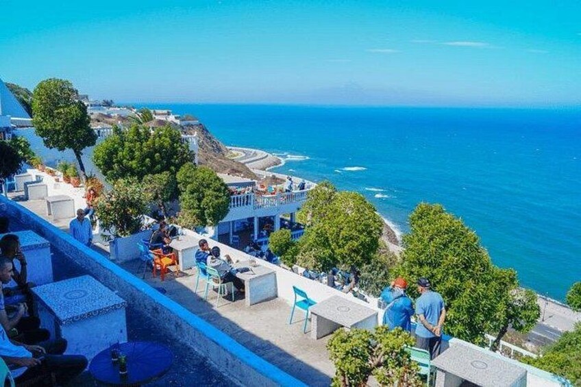 A seaside terrace with people dining, overlooking the ocean and a coastal town. 4