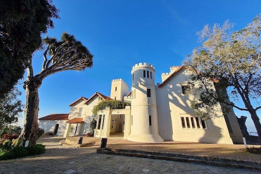A white building with a tower, surrounded by trees and a cobblestone street. 2