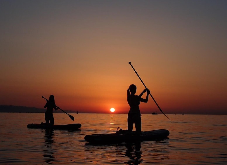 Two people paddleboarding at sunset with the sun setting in the background. 5