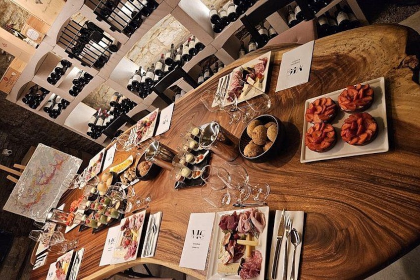 A wine tasting event with a wooden table set with wine glasses, bottles, and food. 4