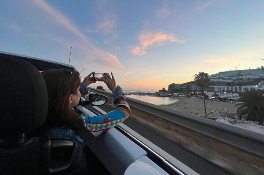 A person taking a photo of a beach and buildings from inside a moving vehicle. 5