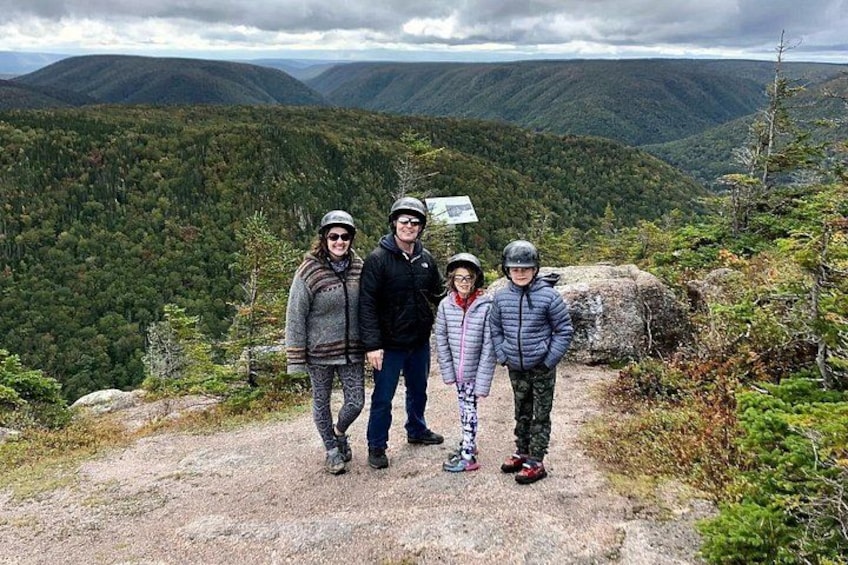 Un grupo de personas de pie sobre un sendero rocoso, con un paisaje montañoso al fondo. 4