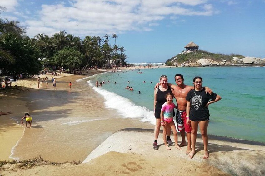 A beach with people, palm trees, and a hill with a structure on top. 4