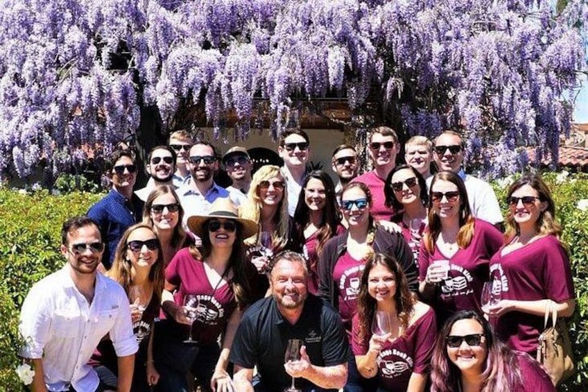 A group of people posing in front of a purple flowering tree. 3