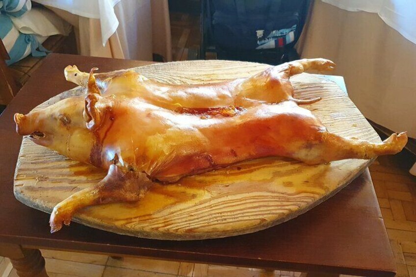 A whole roasted pig on a wooden cutting board. 4